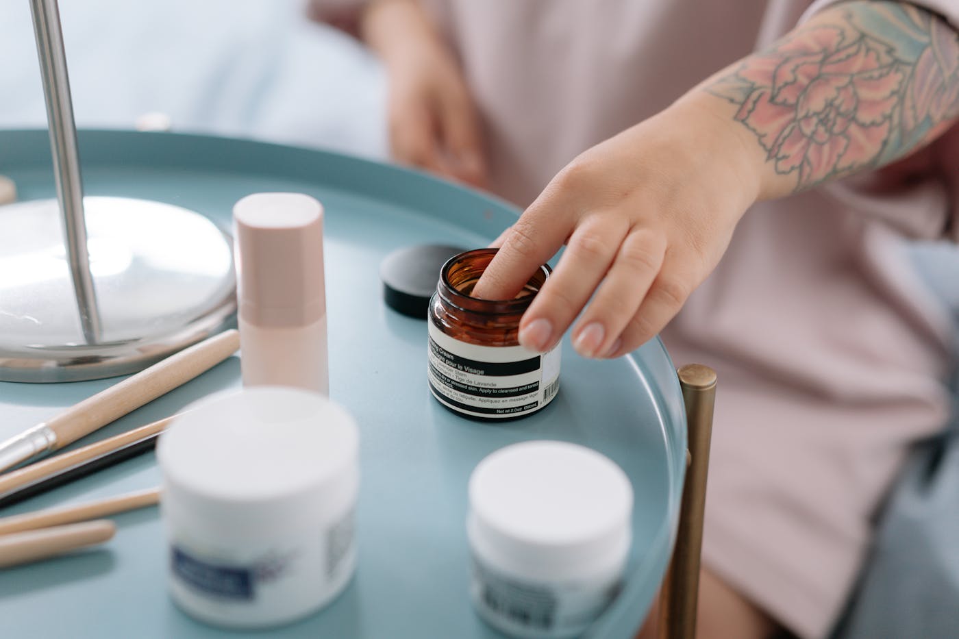 Hand reaching for skincare creams arranged on a salon back-bar tray.
